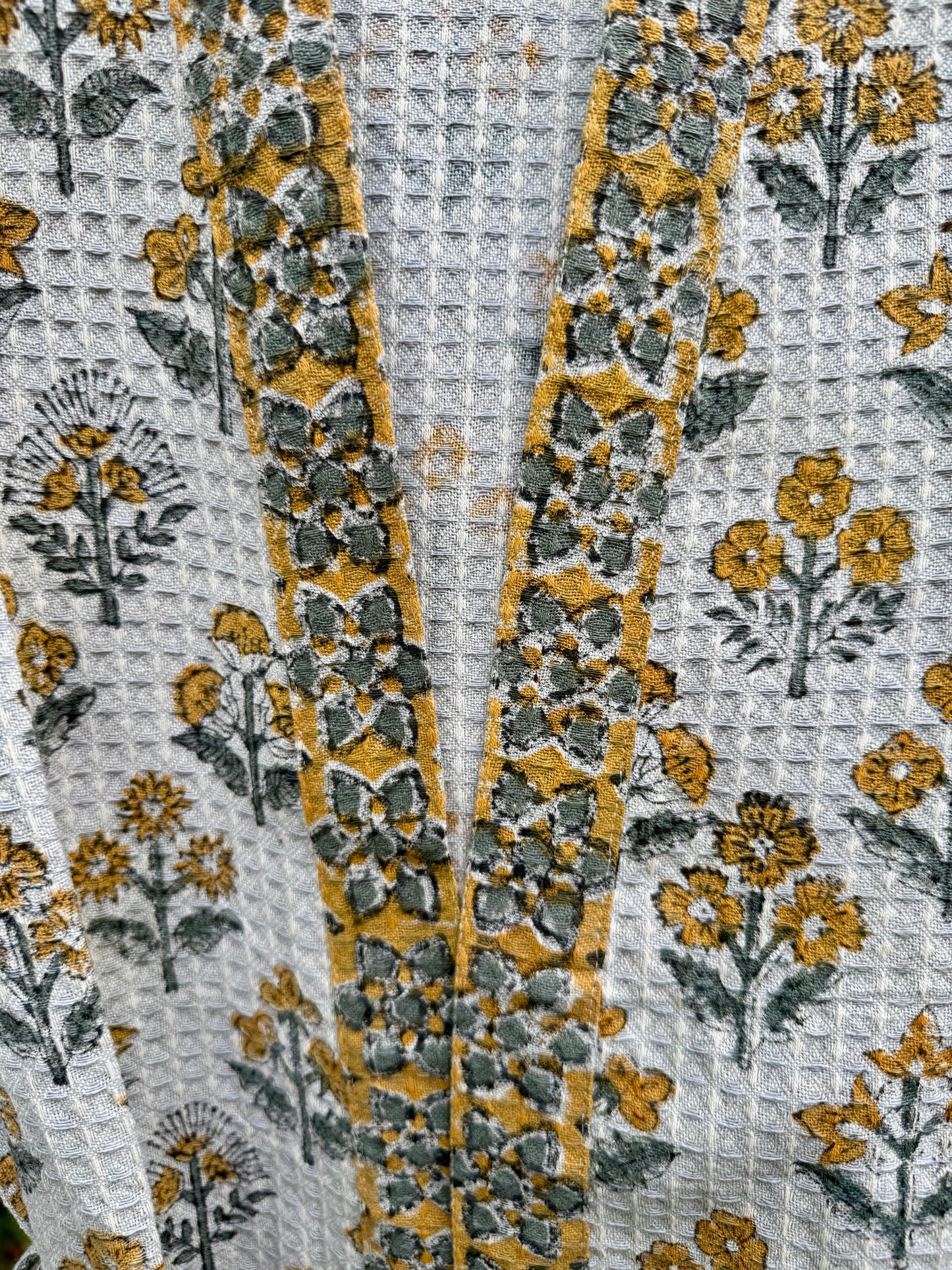 House of Mulmul - cotton bath robe. Close-up of a floral patterned fabric with yellow, green, and gray colors.