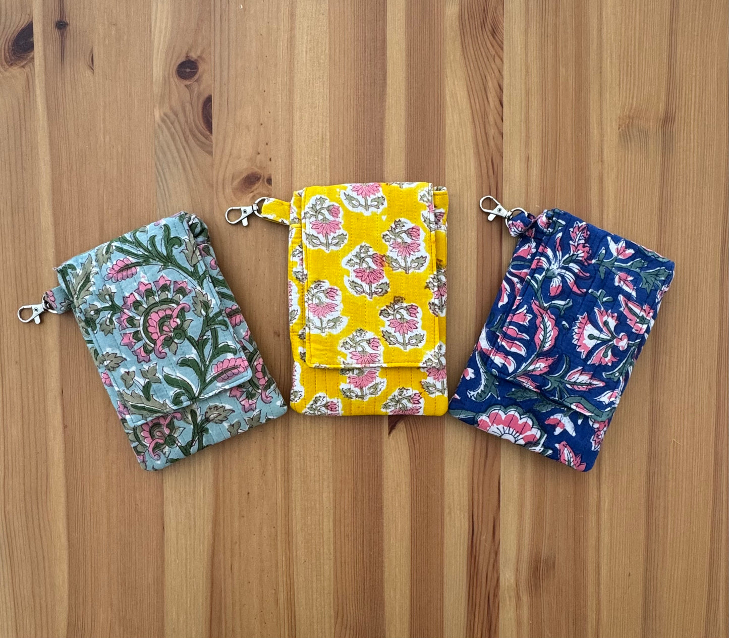 House of Mulmul - Blockprinted Crossbody Mobile Sling Bag. Three floral-patterned mobile pouches on a wooden surface