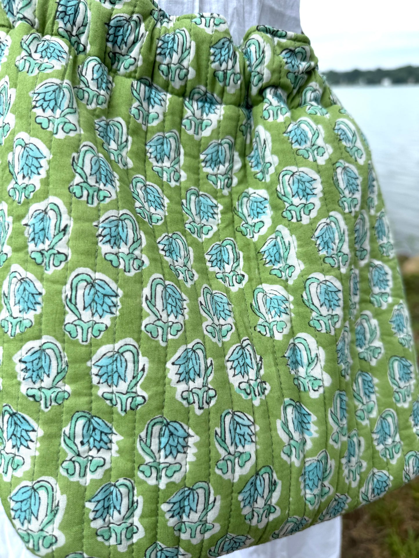 House of Mulmul - Garden Wayfarer Bucket Bag, Cotton bag, Crossbody sling bag. Green fabric with blue floral pattern, possibly a skirt or bag, outdoors.