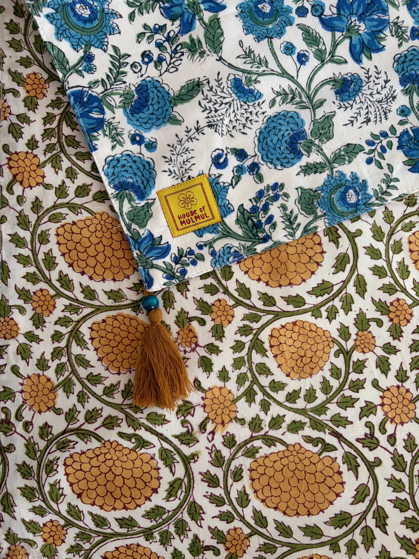 House of Mulmul - Blockprinted Cotton Reversible Table Runner & Placemats set. Fabric with blue floral and brown geometric patterns, featuring a 'Made in India' label.