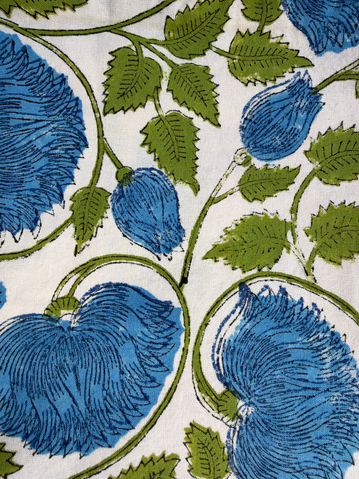 House of Mulmul - Blockprinted Cushion Covers-Pillow Cases. A close-up of a fabric or wallpaper pattern featuring large blue flowers and green leaves on a white background.