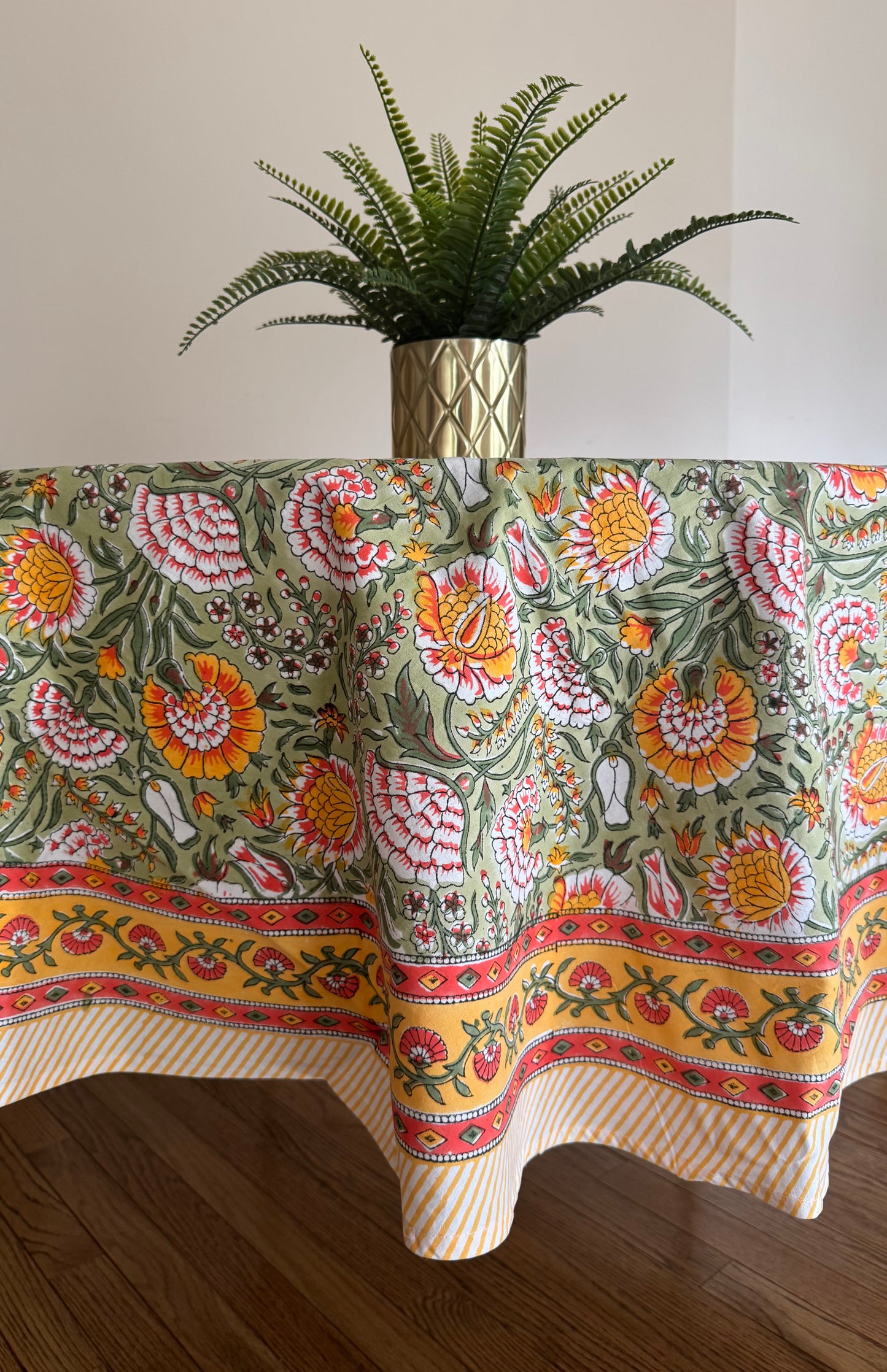 House of Mulmul - Cotton Table Cloth Round. Decorative tablecloth with floral pattern on a table, above a plant.