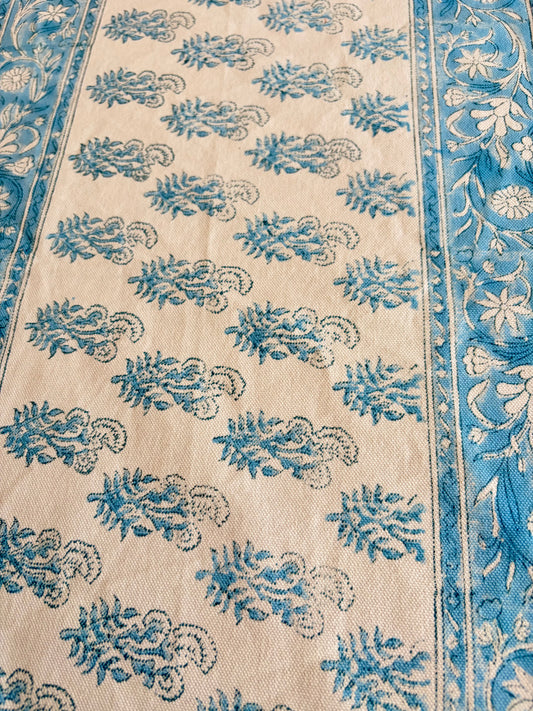House of Mulmul - Cotton Blockprinted Table Runner. Close-up of a patterned table runner with blue and white designs on a beige background