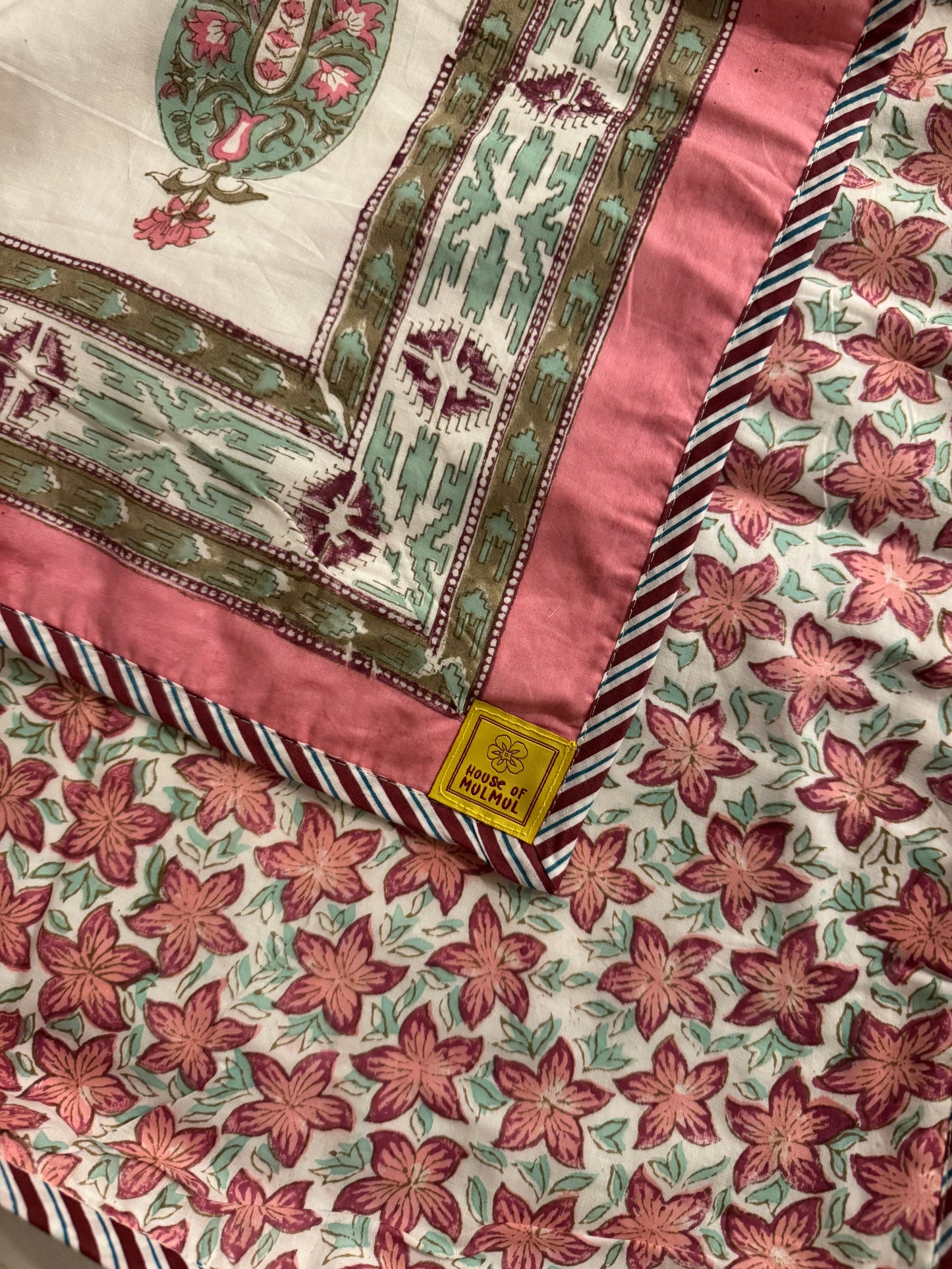 House of Mulmul - Coverlet Dohar, cotton blanket, muslin blanket, mulmul dohar. Close-up of a fabric with floral and geometric patterns, featuring House of Mulmul label.