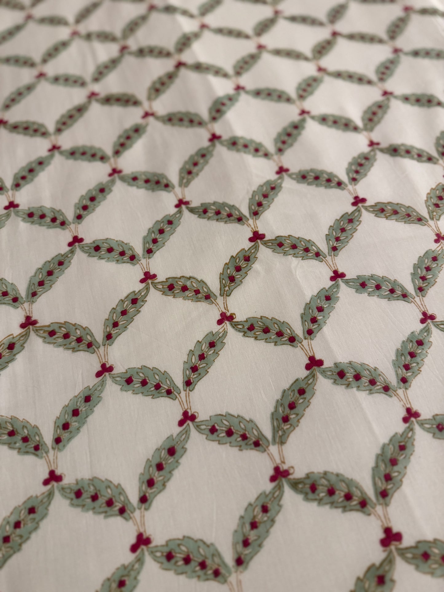 House of Mulmul - Coverlet Dohar, cotton blanket, muslin blanket, mulmul dohar. Decorative handblock printed fabric with patterned fabric with green leaves and red berries on a white background