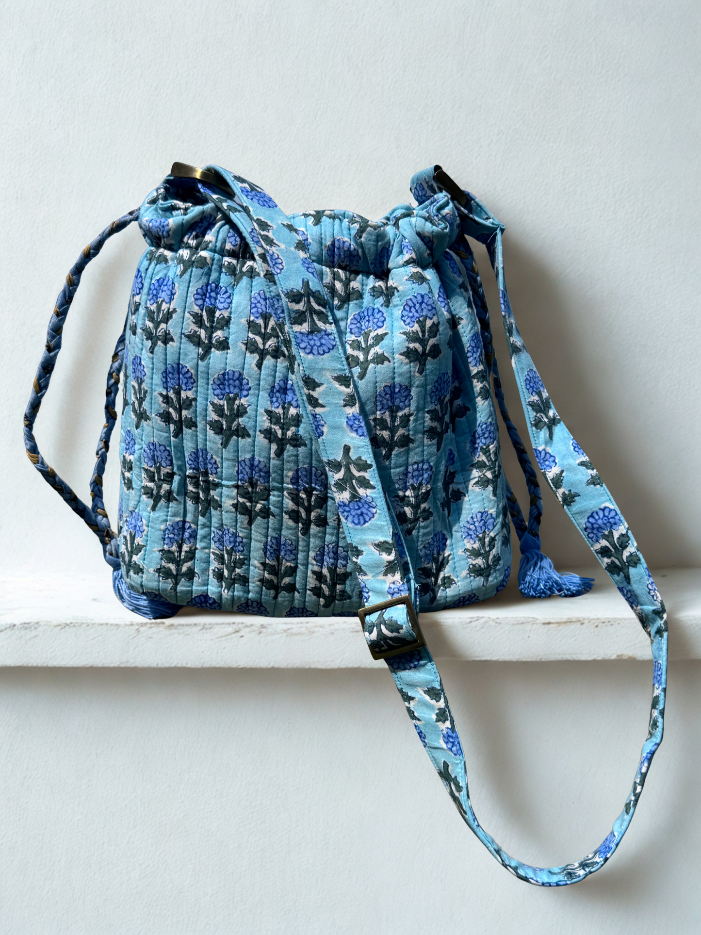 House of Mulmul - Garden Wayfarer Bucket Bag, Cotton bag, Crossbody sling bag. Blue patterned drawstring bag on a white surface