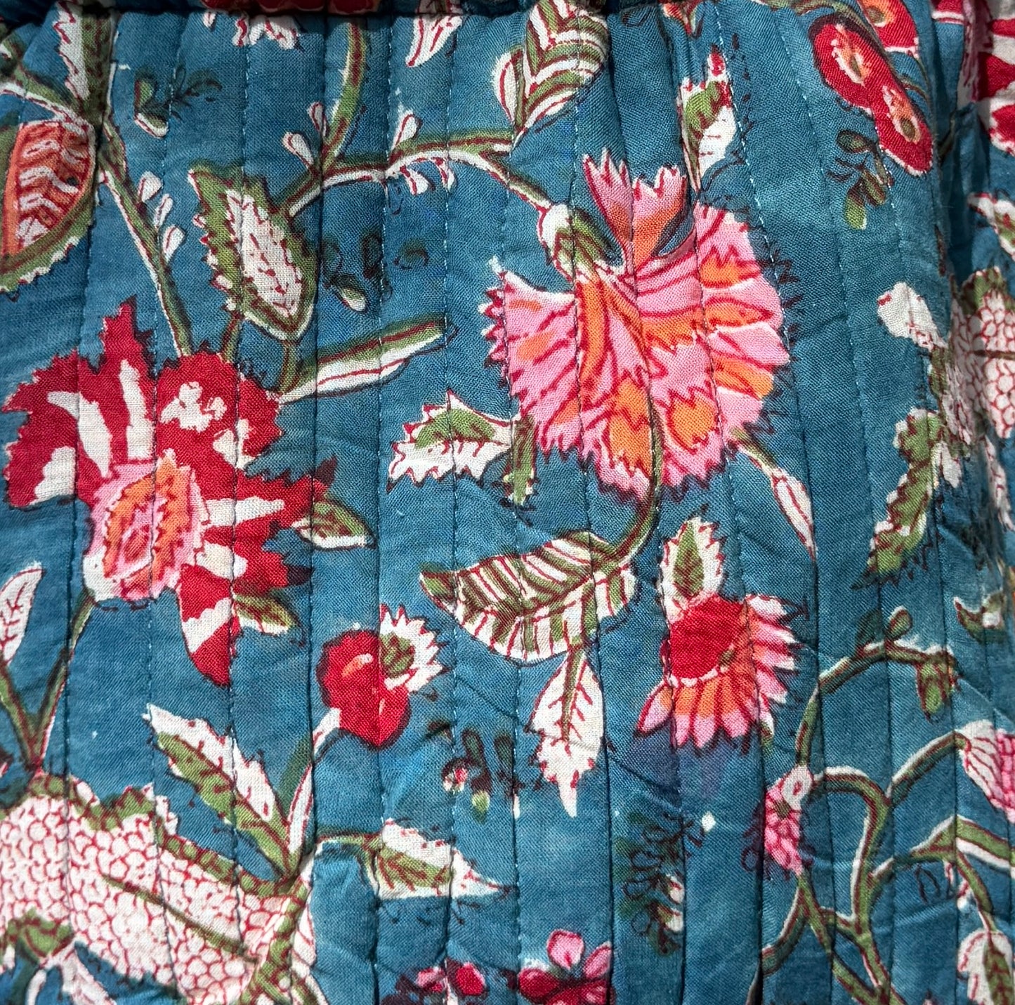 House of Mulmul - Garden Wayfarer Bucket Bag, Cotton bag, Crossbody sling bag. Close-up of floral quilt with red, pink, and white flowers on a blue background