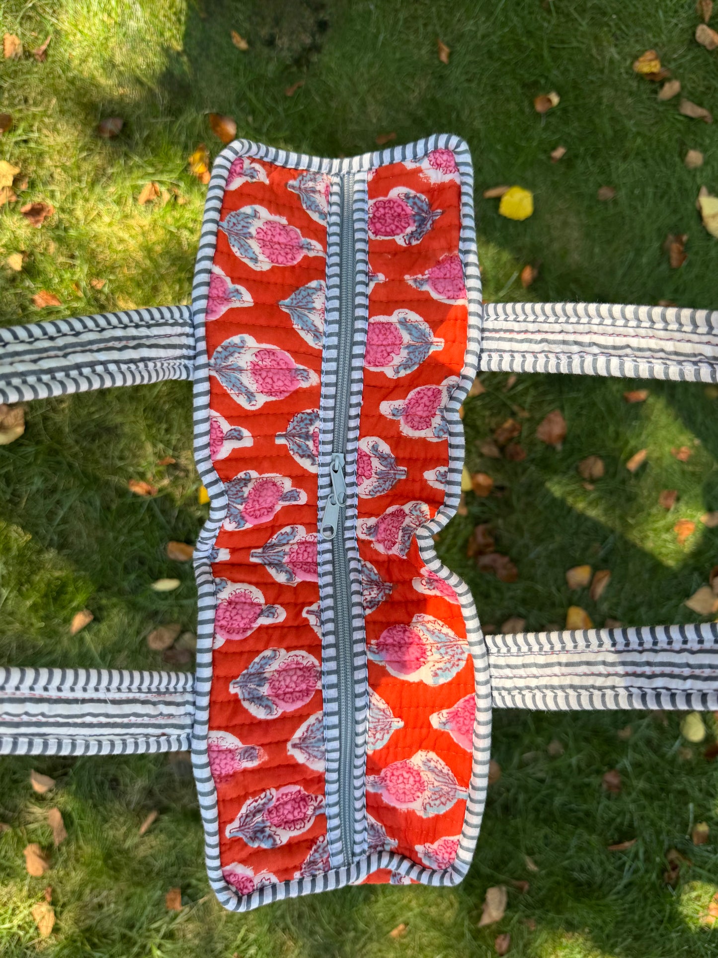 House of Mulmul - Cotton Tote Bag. Orange patterned pouch with striped handles on a grassy background