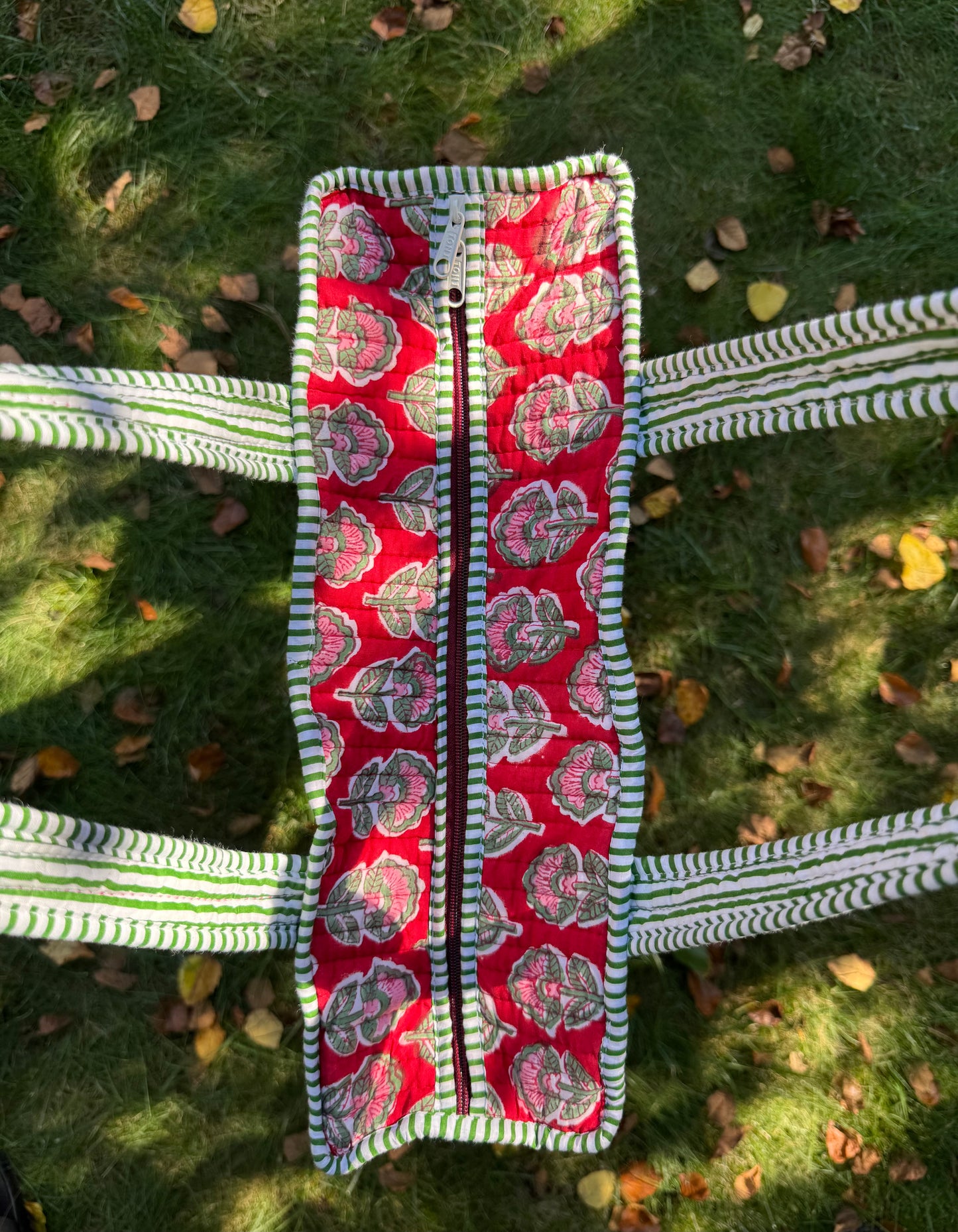 House of Mulmul - Cotton Tote Bag. Red patterned bag with a zipper on a grassy background