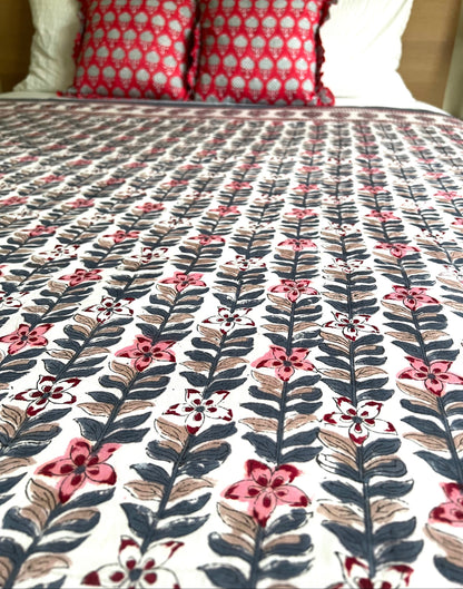 House of Mulmul - Handblock printed cotton summer quilt. Cotton coverlet. Cotton dohar. Muslin blanket. Indian summer quilt. Indian dohar. Floral patterned comforter on a bed with red and white checkered pillows.