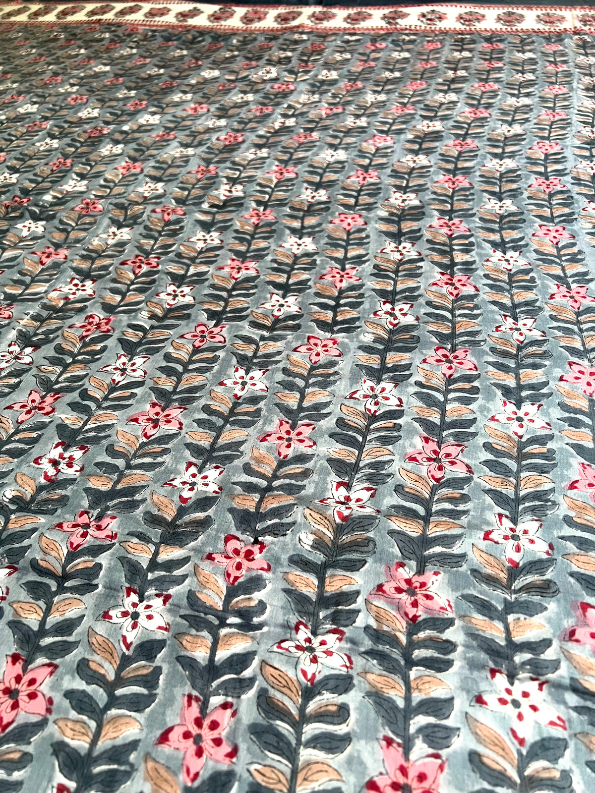 House of Mulmul - Handblock printed cotton summer quilt. Cotton coverlet. Cotton dohar. Muslin blanket. Indian summer quilt. Indian dohar. Floral patterned fabric with pink, white, and green flowers on a gray background