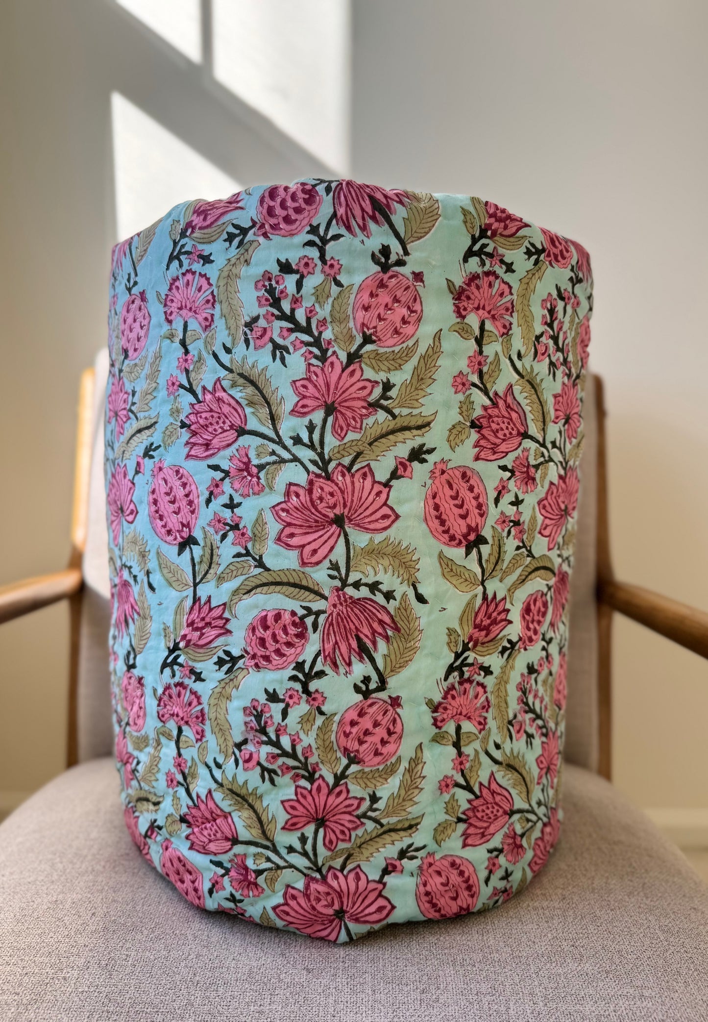 House of Mulmul - Blockprinted Cotton Quilt. Reversible Quilt. Rolled-up quilt with floral and striped patterns.