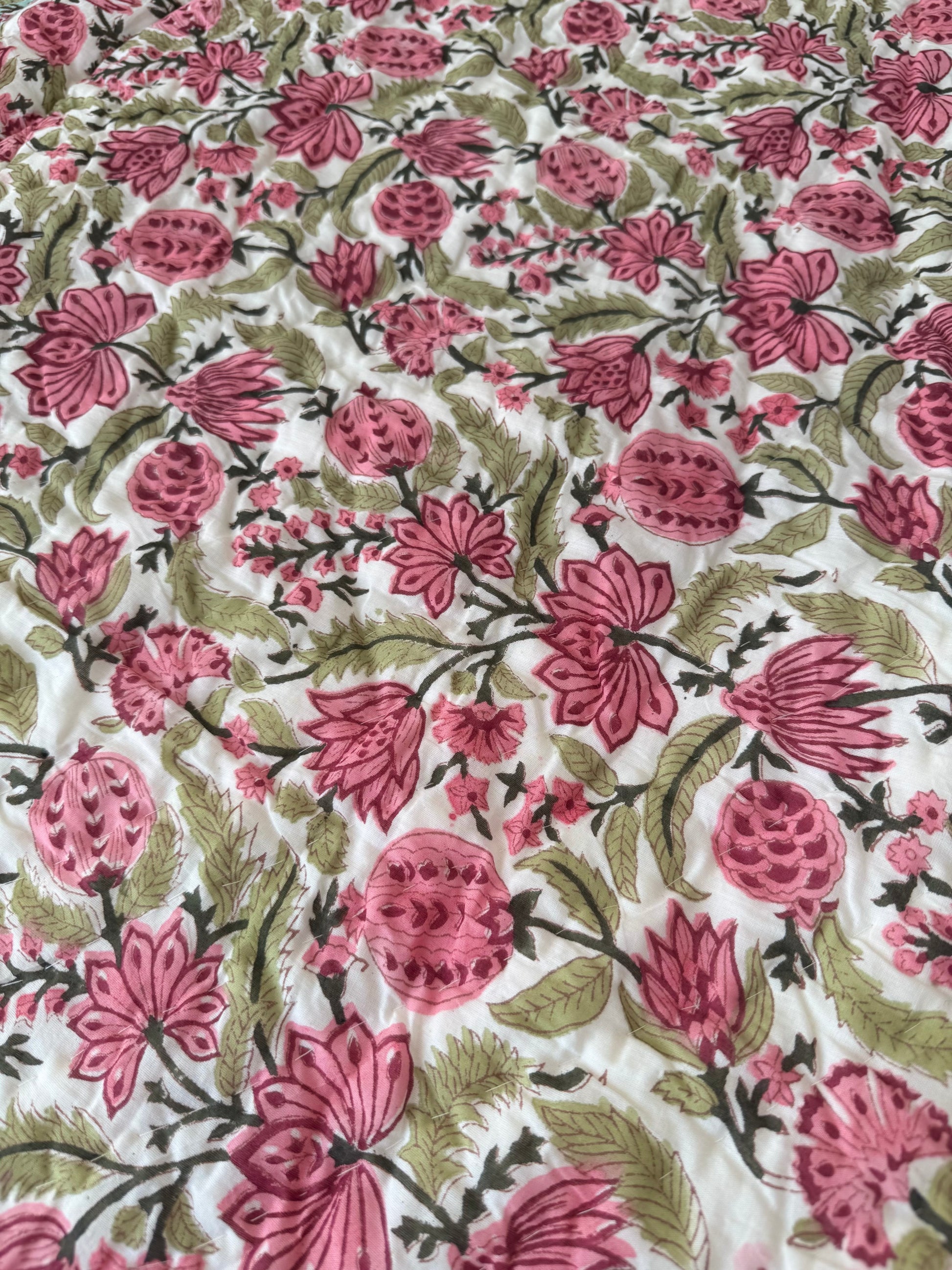 House of Mulmul - Blockprinted Cotton Quilt. Reversible Quilt. Floral patterned fabric with pink flowers and green leaves on a white background