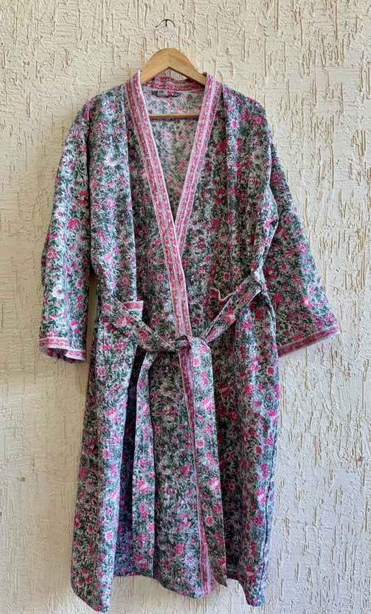 House of Mulmul - Blockprinted Cotton Bathrobe. Floral patterned robe on a wooden hanger against a textured wall.