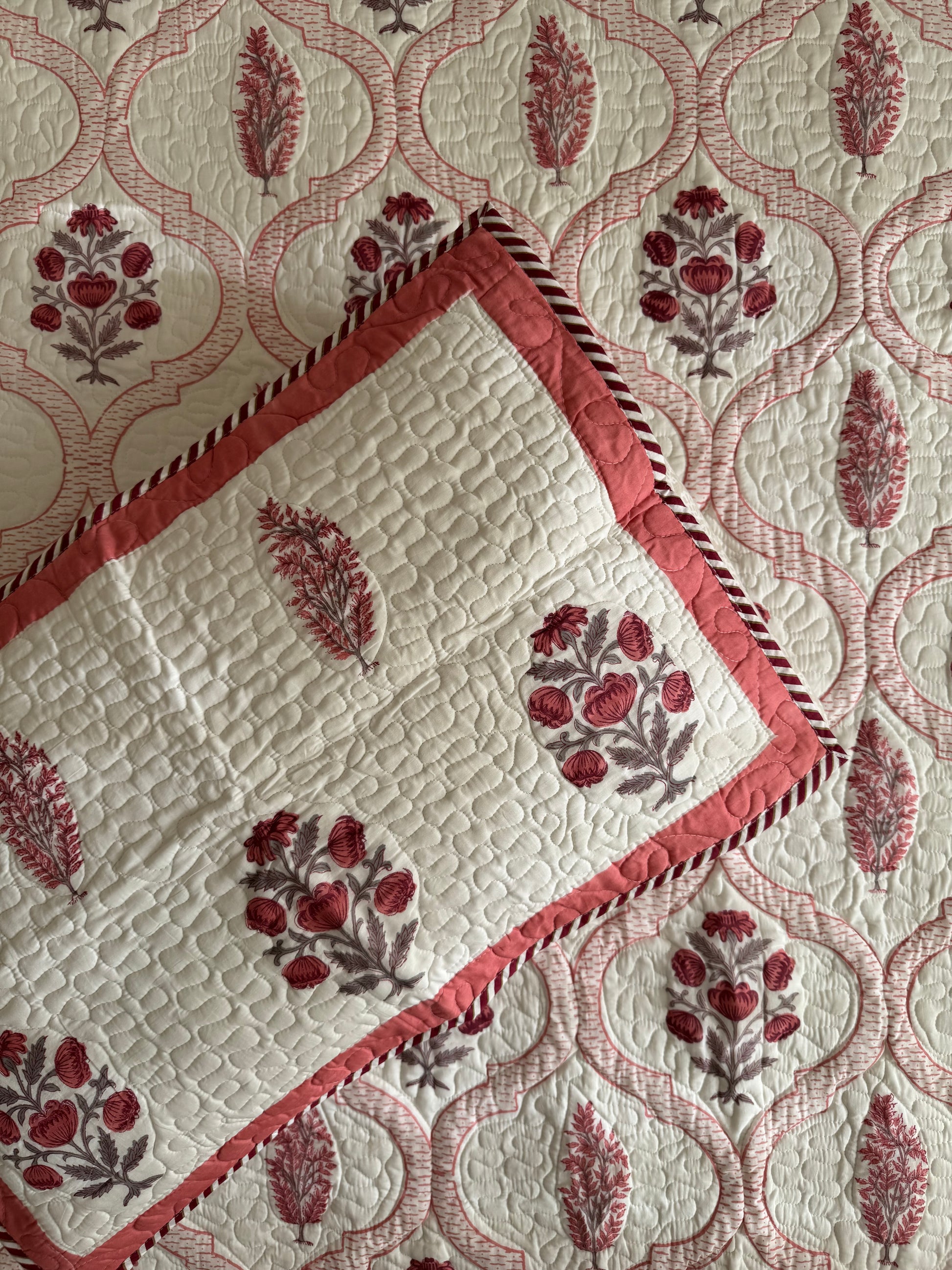 House of Mulmul - Blockprinted Cotton Bedcover Reversible Muslin. Bedspread with floral patterns and red border on a matching pillow covers
