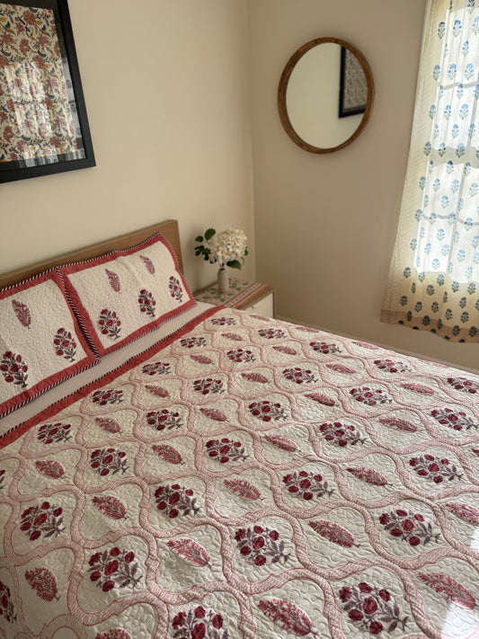 House of Mulmul - Blockprinted Cotton Bedcover Reversible Muslin. Bedroom with floral quilted bedspread, pillows, and decorative elements.