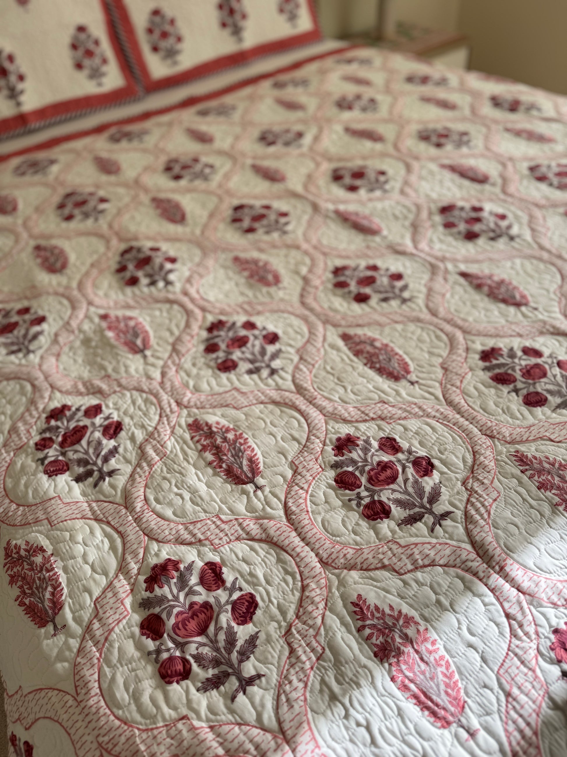 House of Mulmul - Blockprinted Cotton Bedcover Reversible Muslin. Floral patterned bedspread with red and brown designs on a bed.