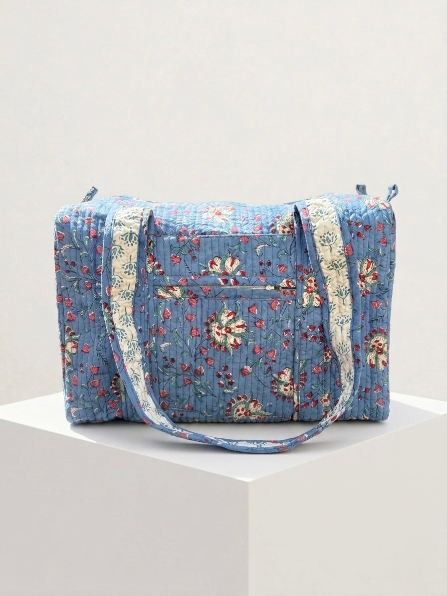 House of Mulmul - Blockprinted Cotton Duffle Bag Weekender Bag. Blue floral-patterned bag with white straps on a light gray background
