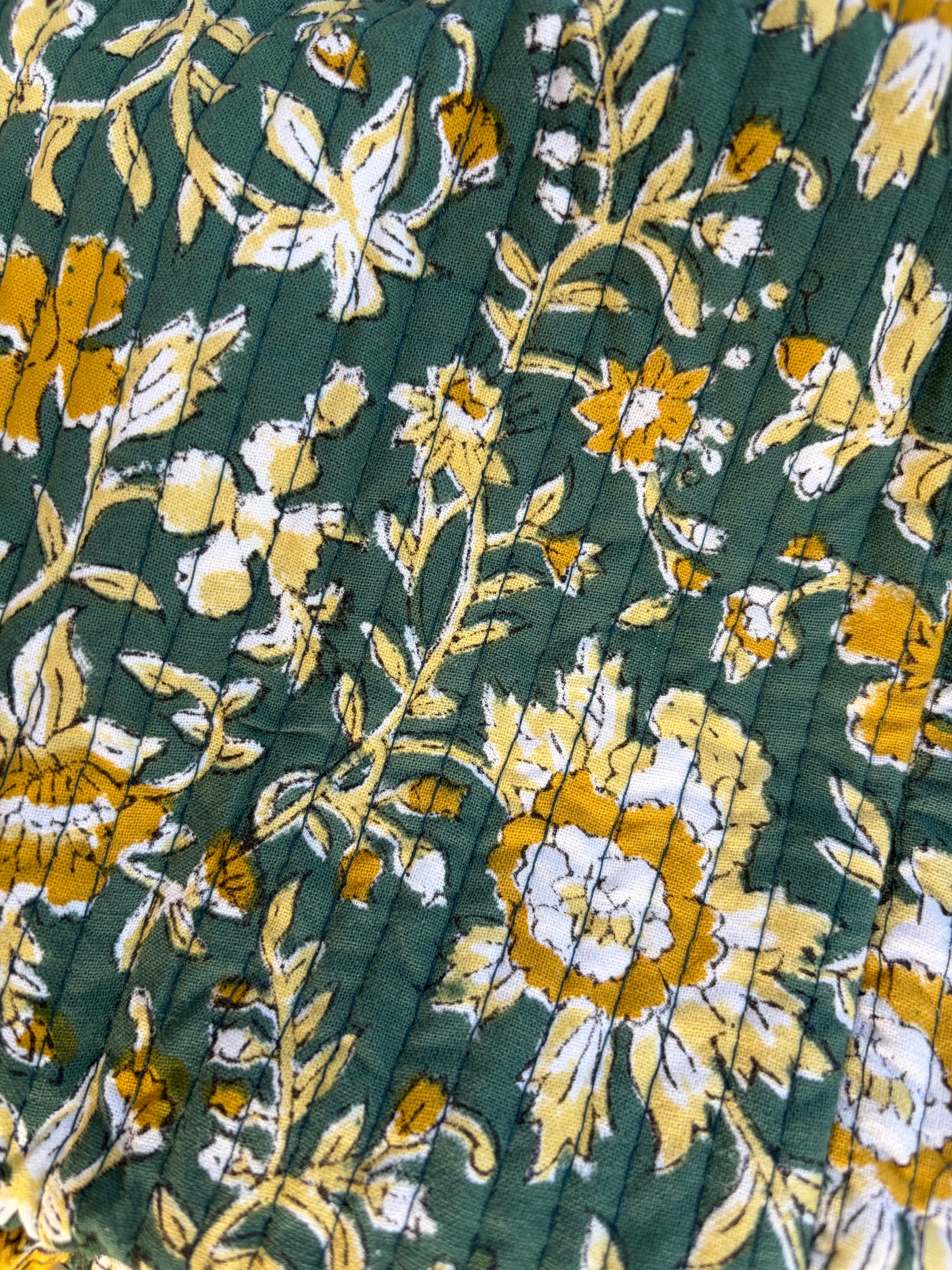 House of Mulmul - Blockprinted Cotton Duffle Bag Weekender Bag. Close-up of pleated fabric with floral pattern on a green background
