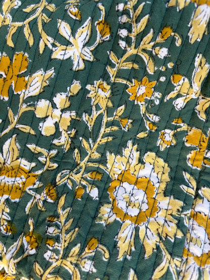 House of Mulmul - Blockprinted Cotton Duffle Bag Weekender Bag. Close-up of pleated fabric with floral pattern on a green background