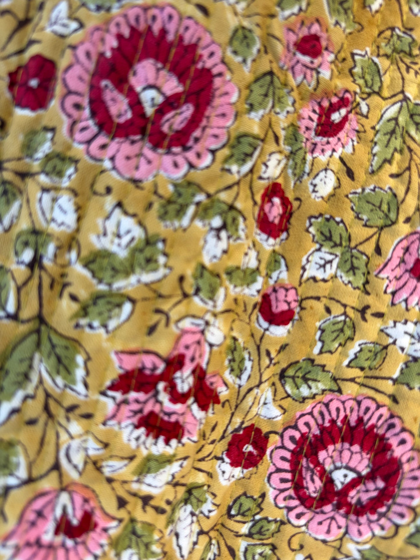 House of Mulmul - Blockprinted Cotton Duffle Bag Weekender Bag. Close-up of floral patterned fabric with pink and red flowers on a yellow background