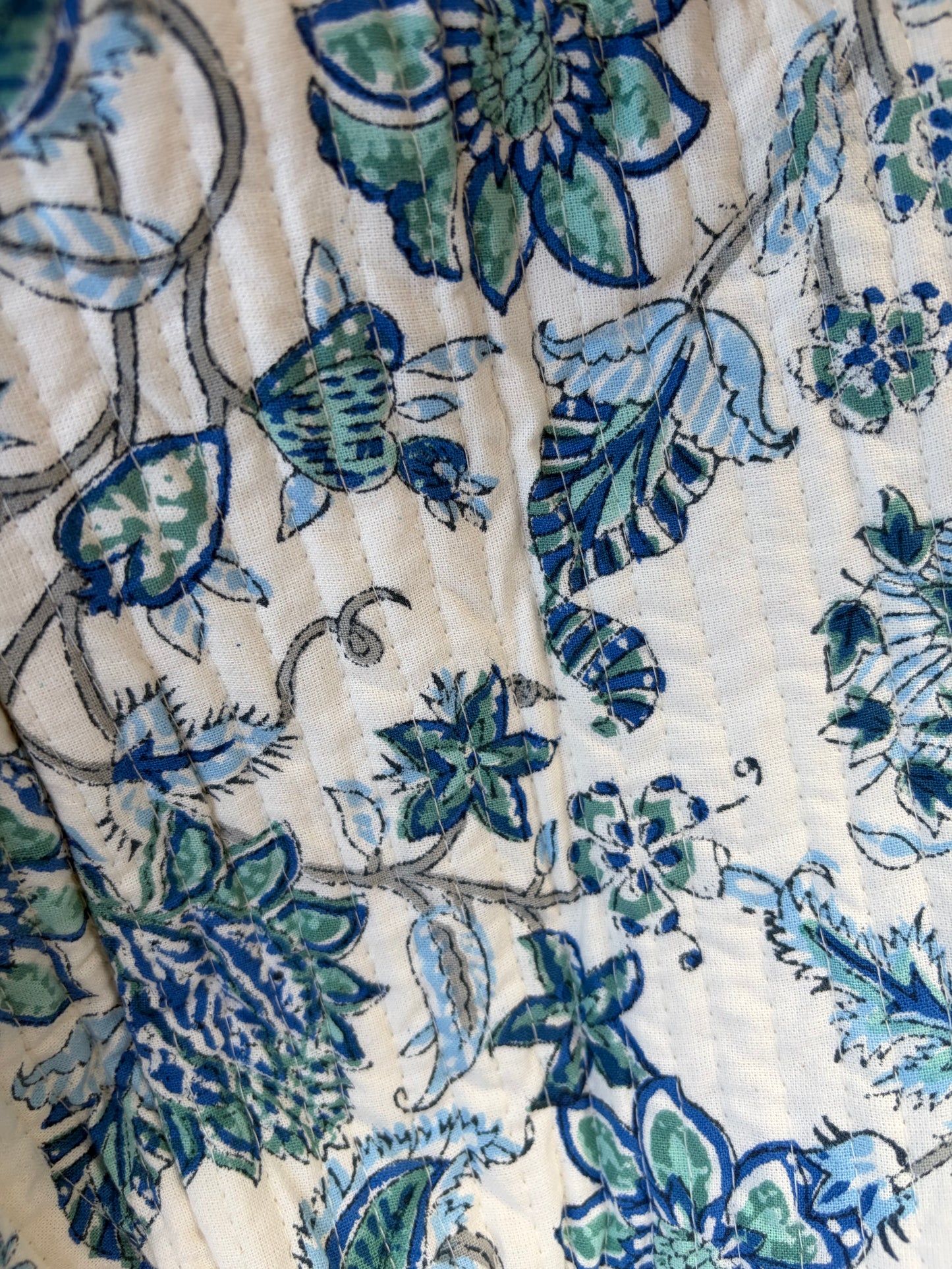 House of Mulmul - Blockprinted Cotton Duffle Bag Weekender Bag. Close-up of a floral pattern with blue and green colors on a textured surface.