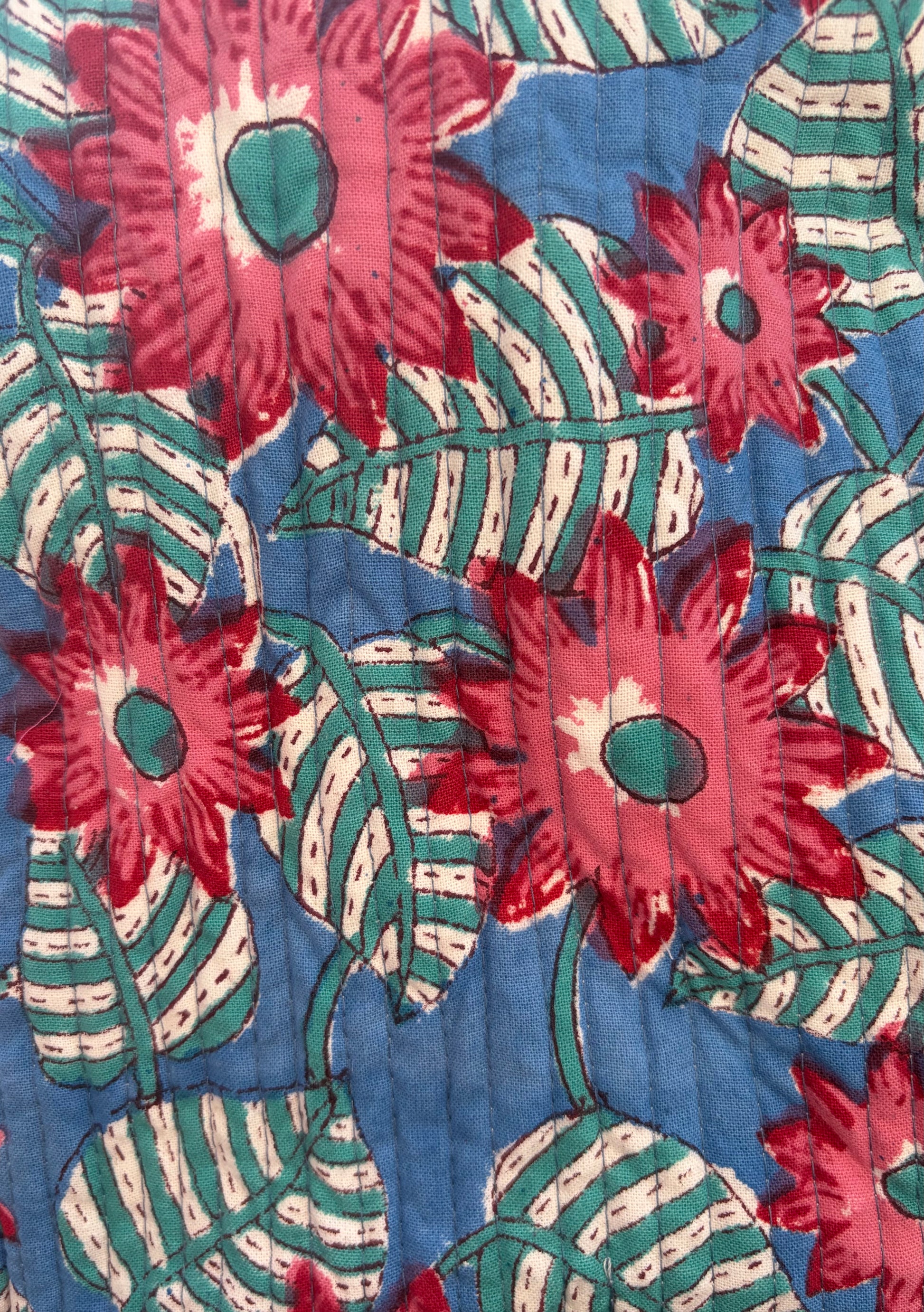 House of Mulmul - Blockprinted Cotton Duffle Bag Weekender Bag. Close-up of a floral patterned fabric with red flowers and green leaves on a blue background.
