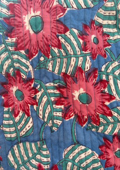 House of Mulmul - Blockprinted Cotton Duffle Bag Weekender Bag. Close-up of a floral patterned fabric with red flowers and green leaves on a blue background.