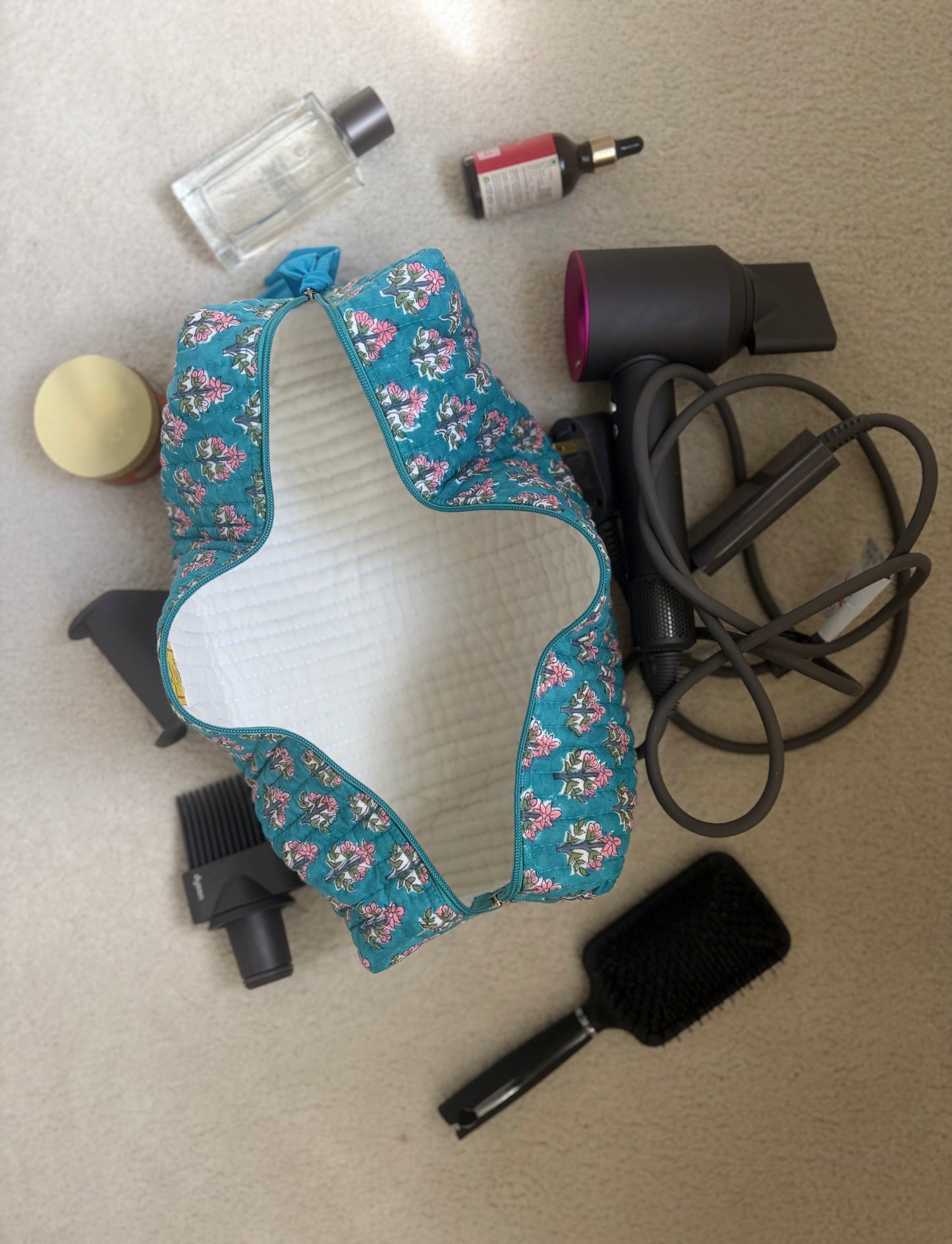 House of Mulmul - Blockprinted Cotton Hair Tool Bag. Floral-patterned Dyson hair dryer and straightener kit with a hair dryer, brush, and other items on a flat surface.