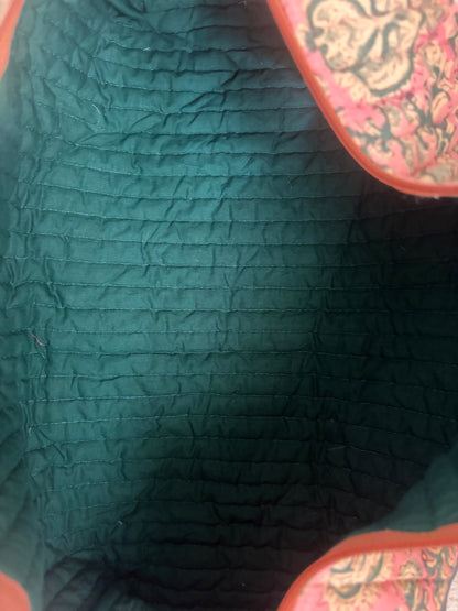 House of Mulmul - Blockprinted Cotton Hair Tool Bag. Close-up of a textured green hair tool bag with a colorful patterned object partially visible.