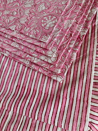 House of Mulmul - Blockprinted Cotton Placemats and Napkins. Close-up of a pink and white patterned placemats with floral napkins and striped designs.