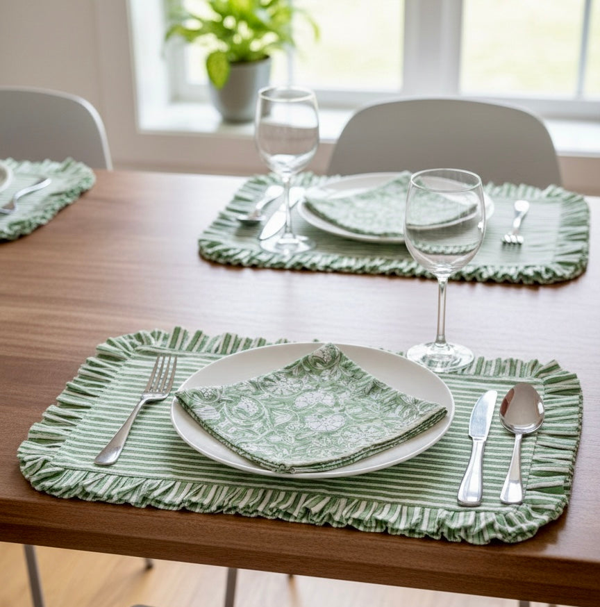 House of Mulmul - Blockprinted Cotton Placemats and Napkins. Dining table set with green placemats, plates, and cutlery in a bright room.