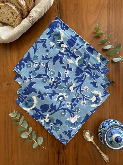 House of Mulmul - Blockprinted Cotton Table Napkins. Set of blue floral-patterned napkins on a wooden surface with bread and a teapot.