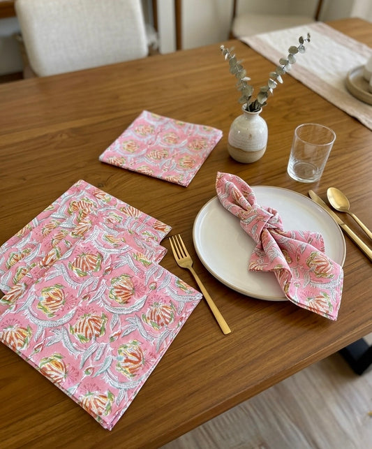 House of Mulmul - Blockprinted Cotton Table Napkins. Dining table setting with pink patterned napkins, plates, and cutlery.