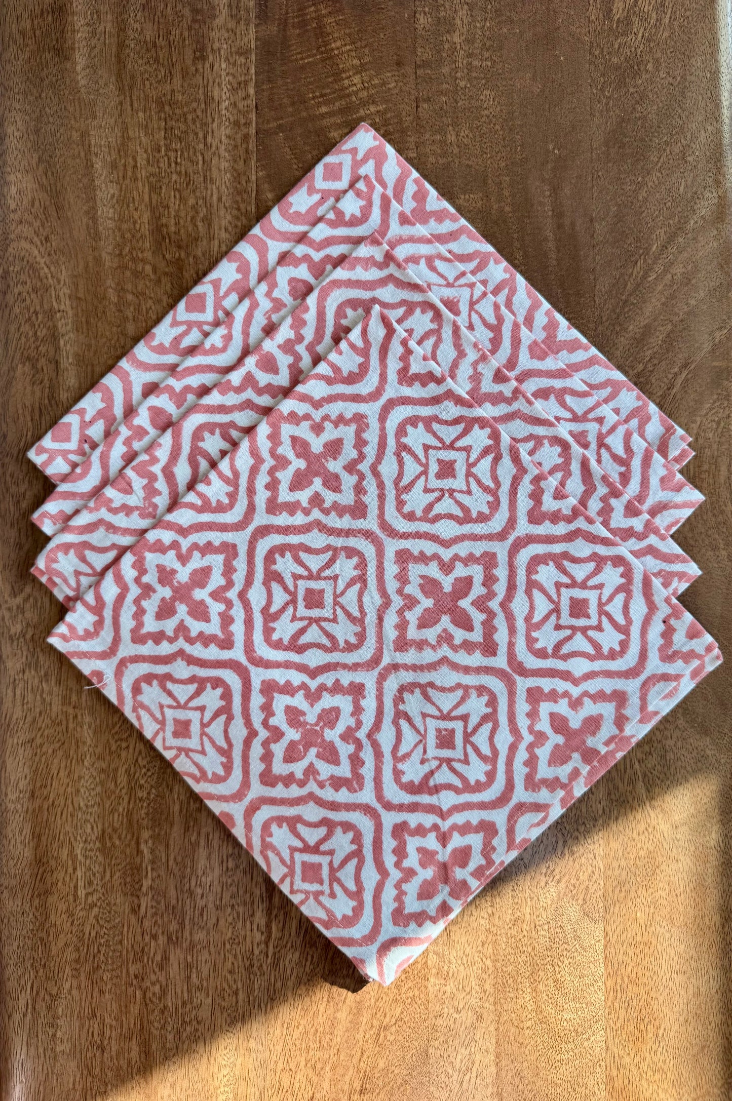 House of Mulmul - Blockprinted Cotton Napkins. Red & Pink patterned napkin on a white plate on a wooden table.