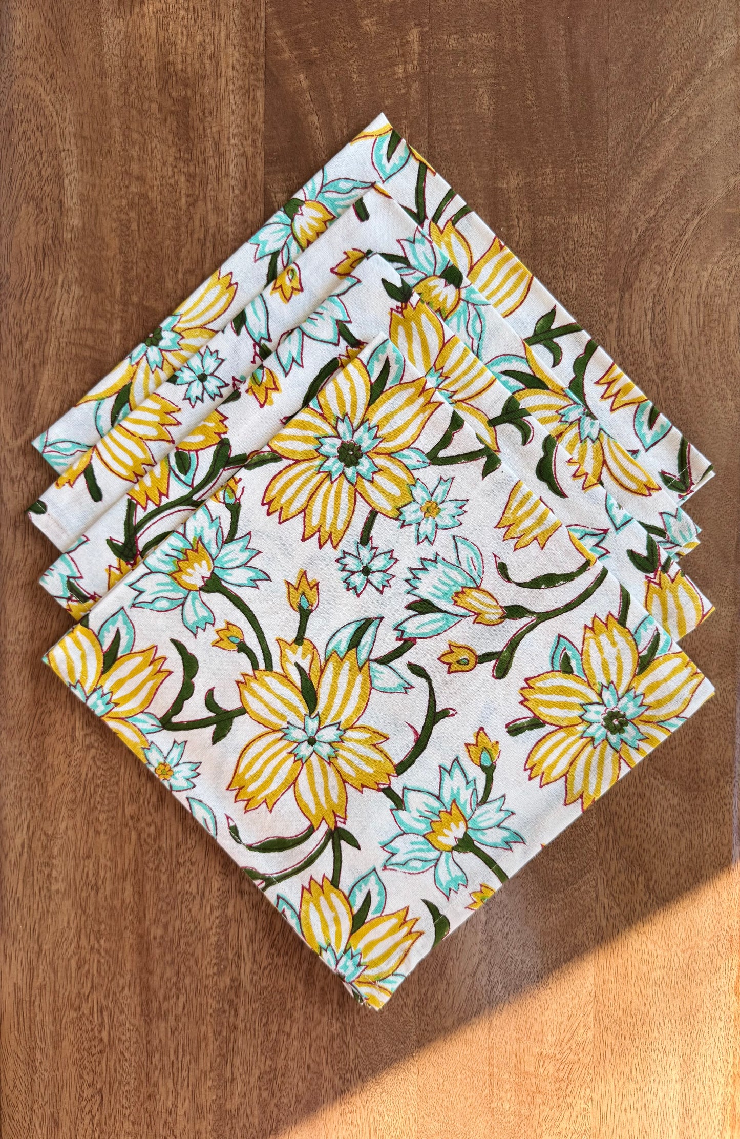 House of Mulmul - Blockprinted Cotton Napkins. Floral-patterned napkins on a wooden surface