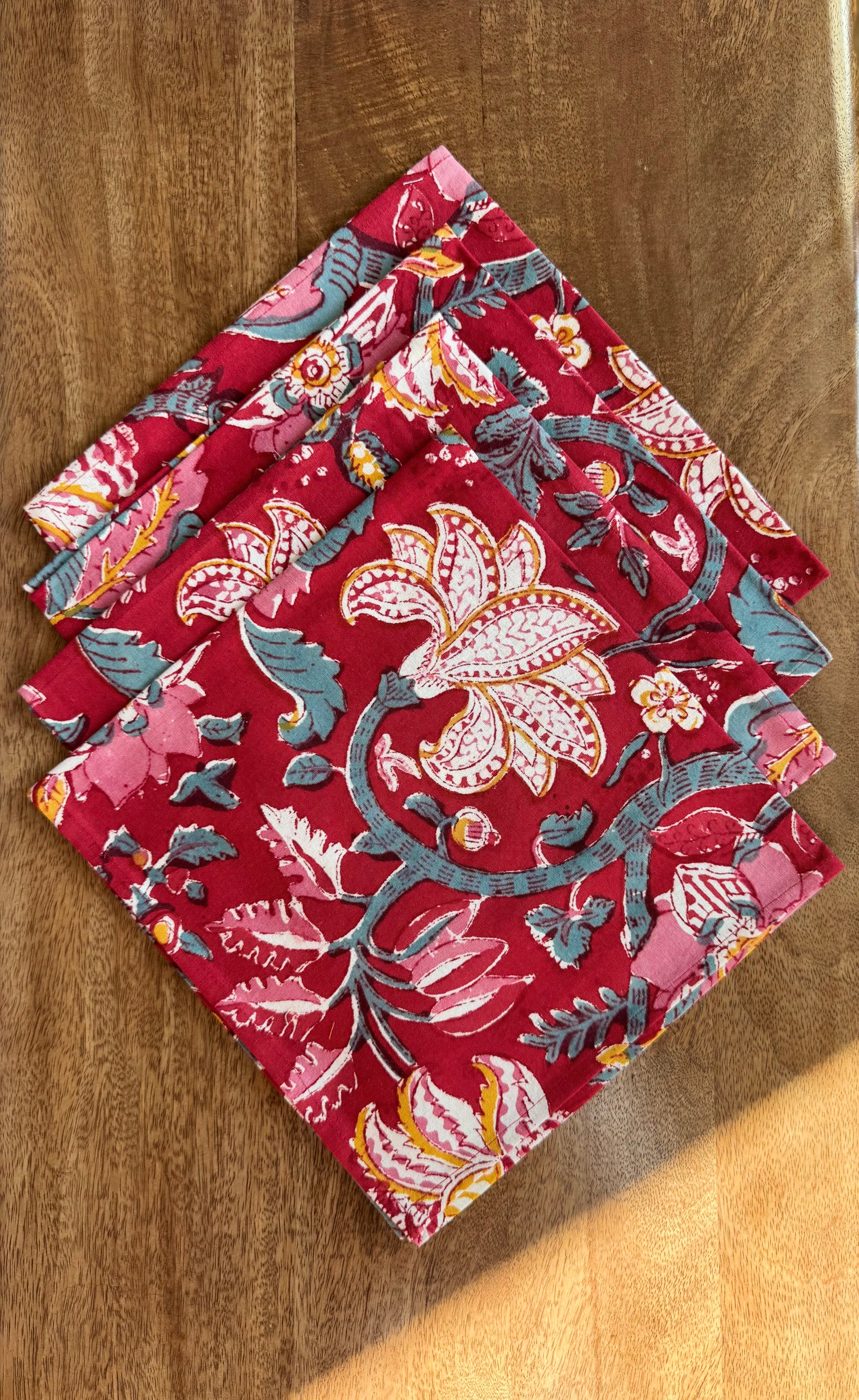 House of Mulmul - Blockprinted Cotton Napkins. Red floral patterned napkins on a wooden surface