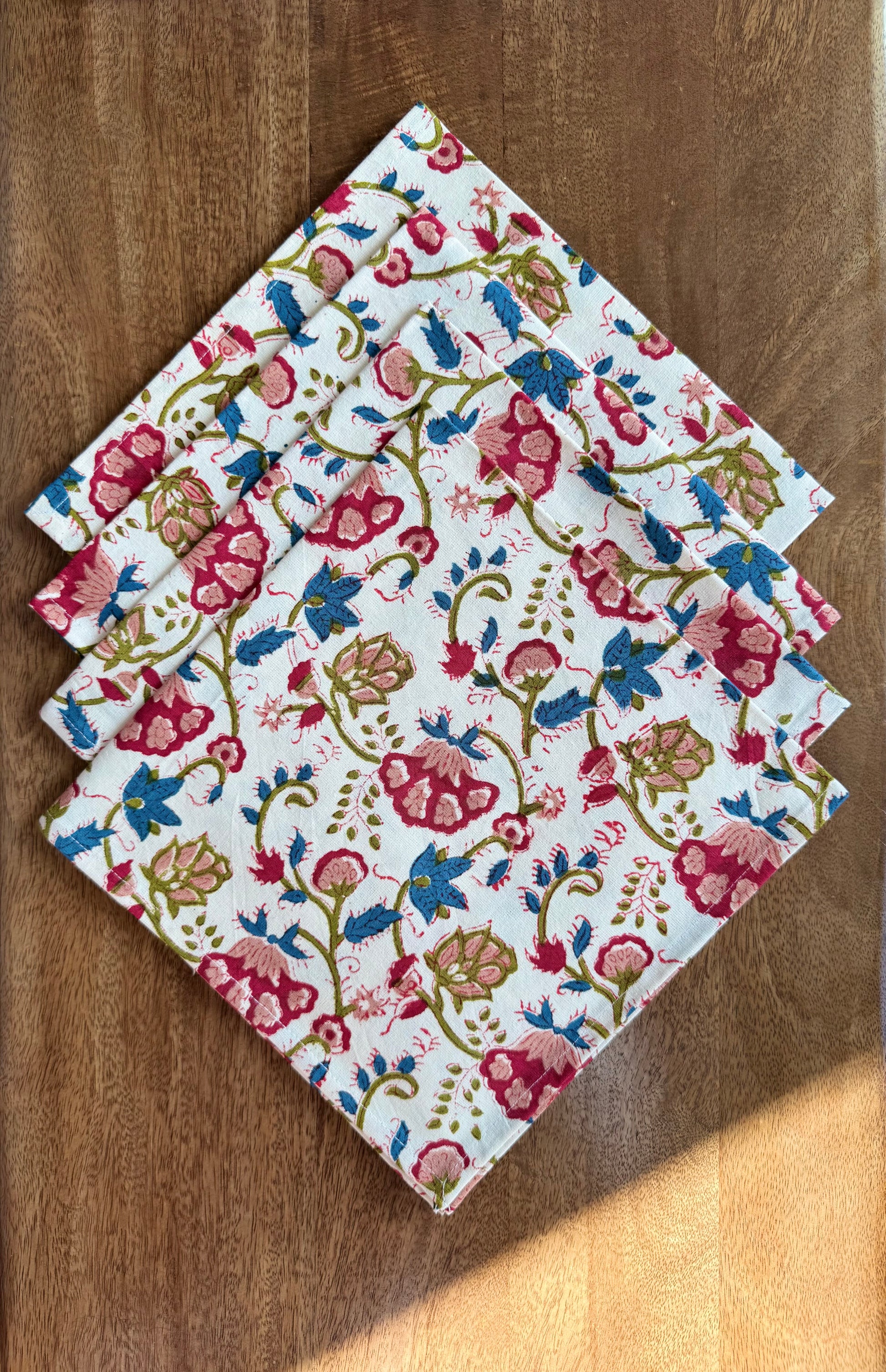 House of Mulmul - Blockprinted Cotton Napkins. Set of floral patterned napkins on a wooden surface