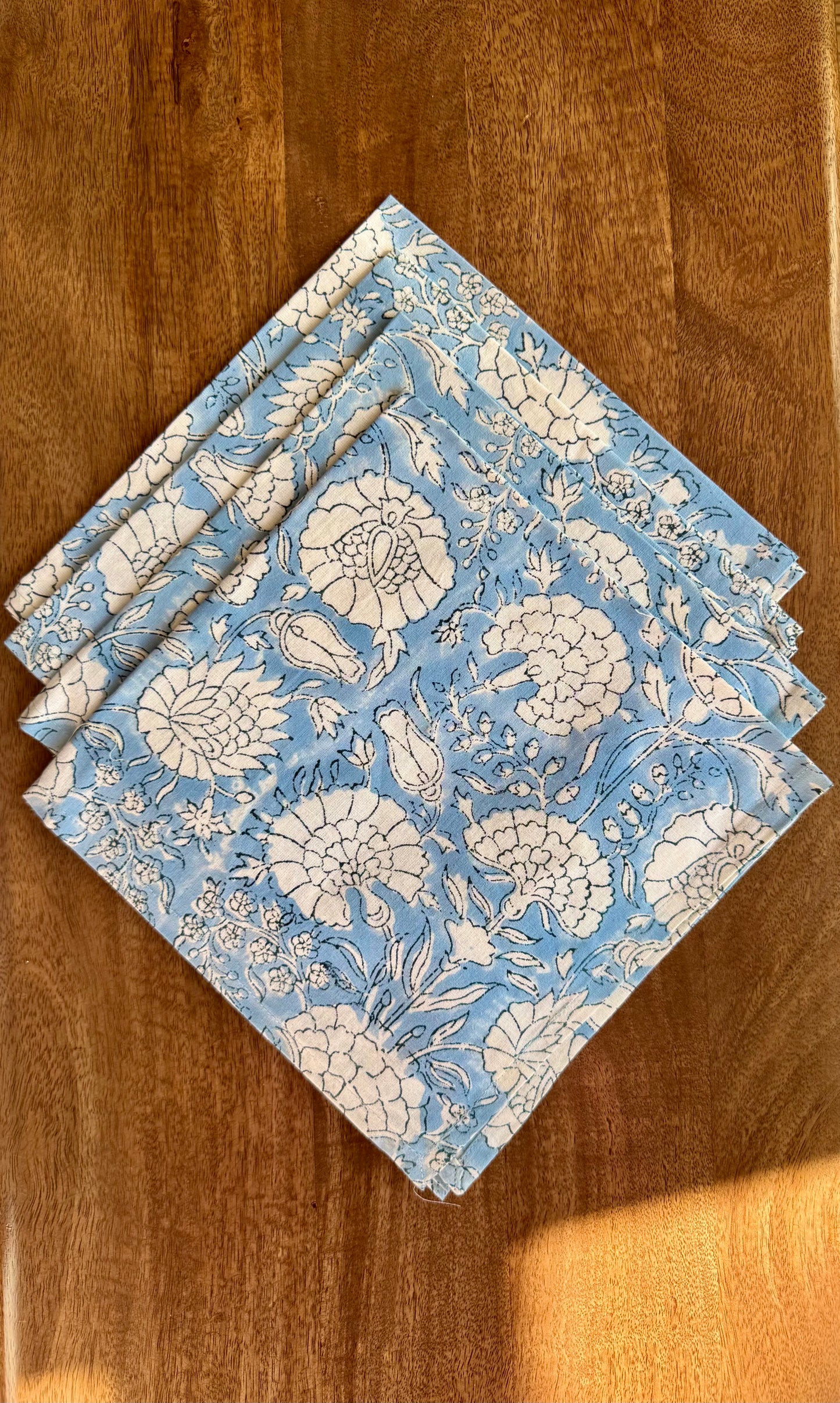House of Mulmul - Blockprinted Cotton Napkins. Set of blue floral patterned napkins on a wooden surface