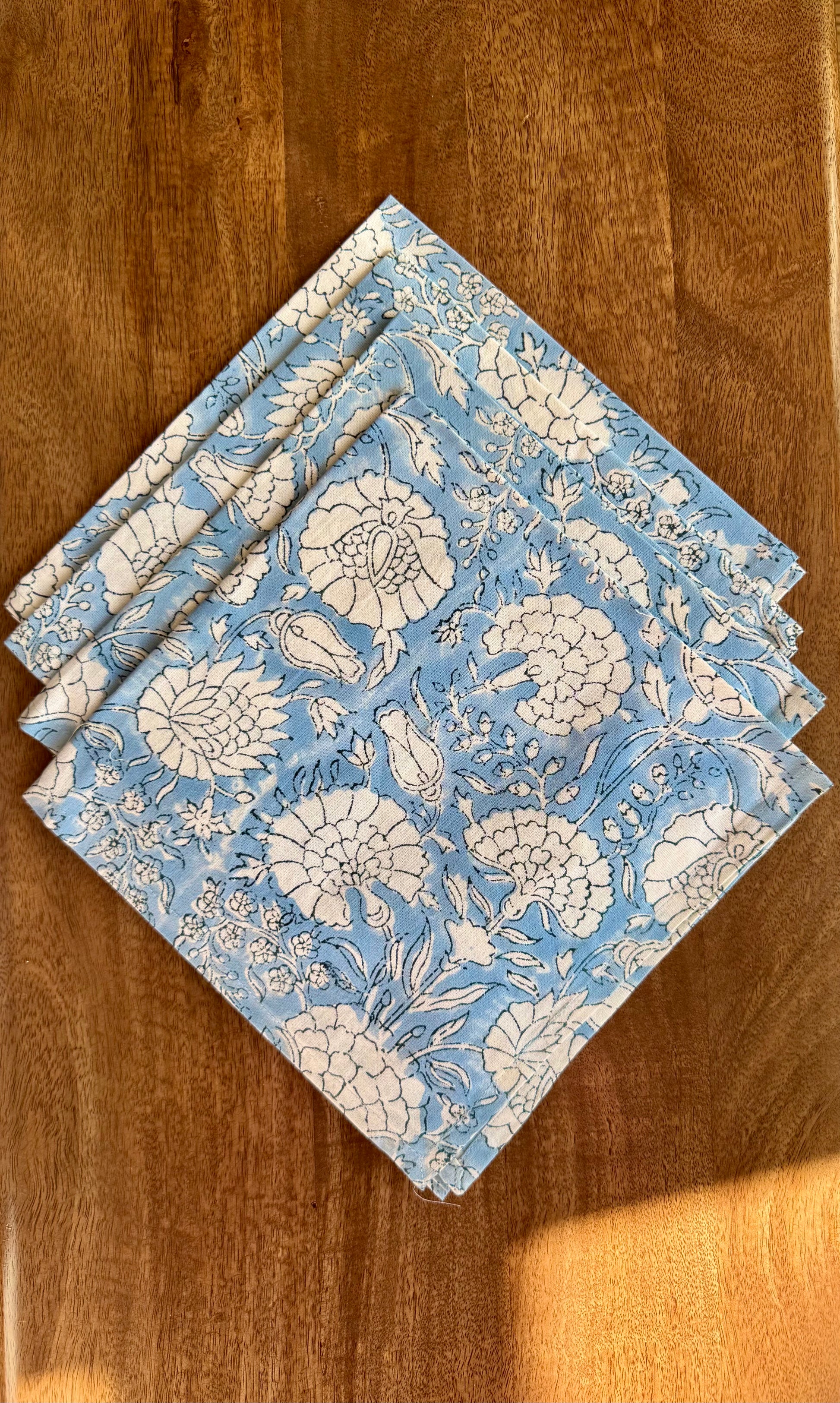 House of Mulmul - Blockprinted Cotton Napkins. Set of blue floral patterned napkins on a wooden surface