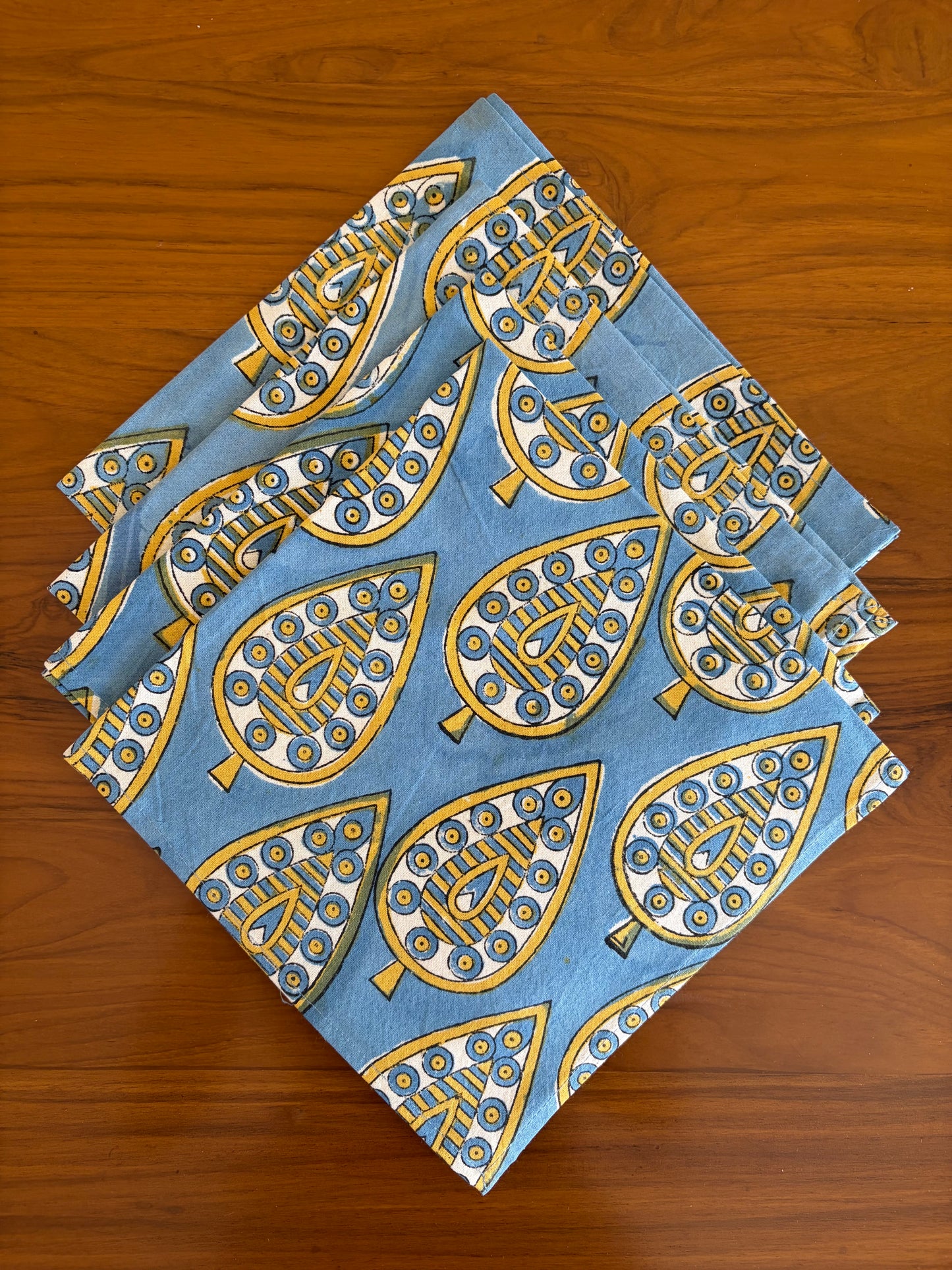 House of Mulmul - Blockprinted Cotton Table Napkins. Set of blue napkins with gold leaf patterns on a wooden surface