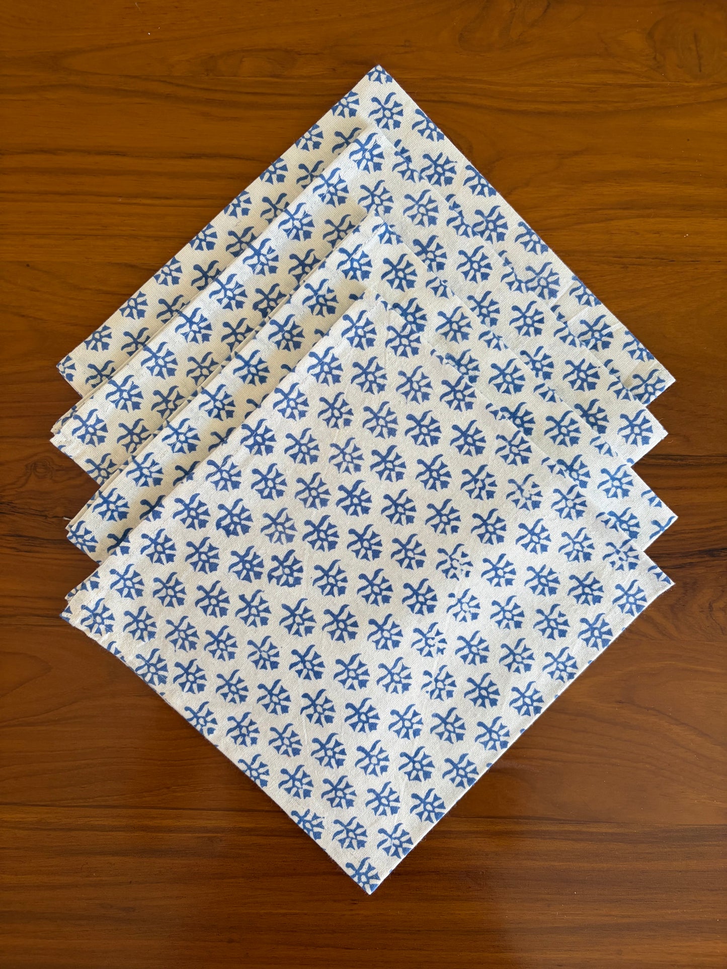House of Mulmul - Blockprinted Cotton Table Napkins. Set of four folded fabric napkins with blue floral pattern on a wooden surface