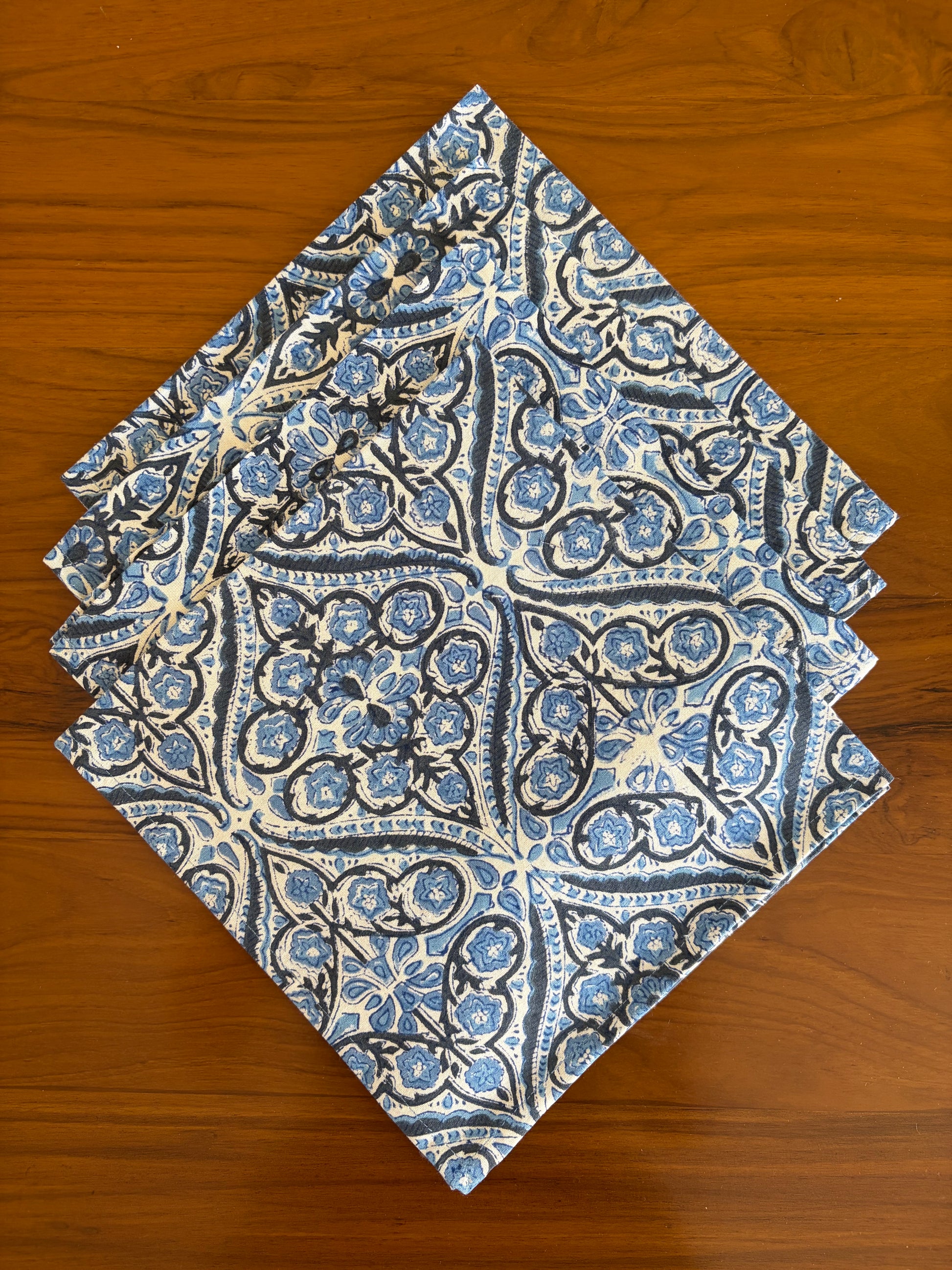 House of Mulmul - Blockprinted Cotton Table Napkins. Folding blue and white patterned table napkins on a wooden surface