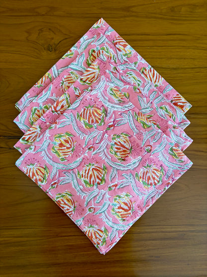 House of Mulmul - Blockprinted Cotton Table Napkins. Set of pink fabric squares napkins with colorful patterns on a wooden surface