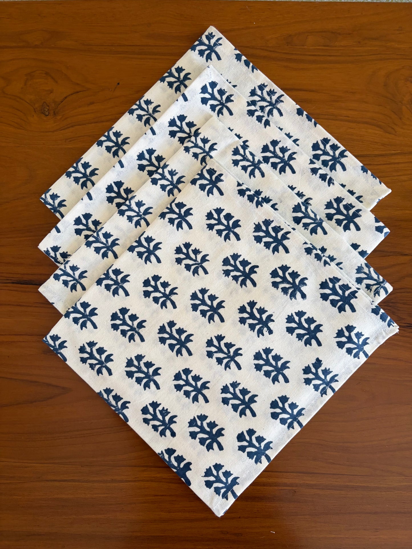 House of Mulmul - Blockprinted Cotton Table Napkins. Set of white with blue floral patterned cotton napkins on a wooden surface