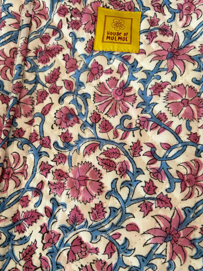 House of Mulmul - Blockprinted Cotton Tote Bag, Travel Bag. A close-up of a printed tote bag with a cream background, pink floral motifs, and blue vine patterns, featuring a yellow fabric label that reads 'HOUSE OF MULMUL'.