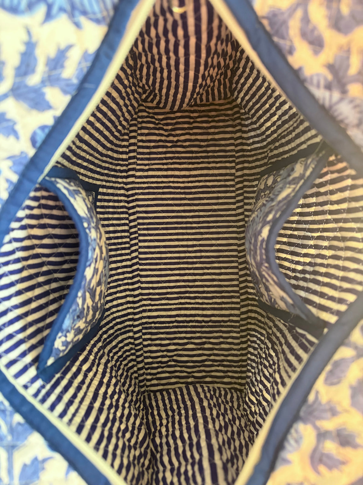 House of Mulmul - Blockprinted Cotton Tote Bag, Travel Bag. Close-up view from inside a striped tote bag, showing navy and beige horizontal stripes with blue trim and a blue floral patterned exterior visible at the edges.