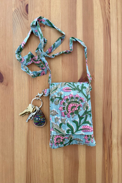House of Mulmul - Blockprinted Crossbody Mobile Sling Bag. Floral patterned keychain with a small pouch on a wooden surface