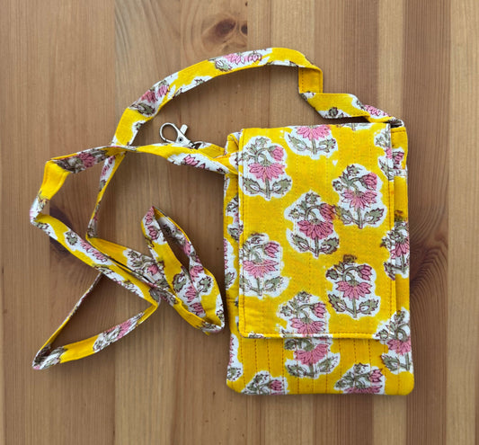 House of Mulmul - Blockprinted Crossbody Mobile Sling Bag. Yellow floral-patterned mobile bag with strap on a wooden surface