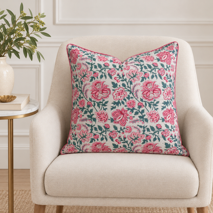 House of Mulmul - Blockprinted Cushion Covers-Pillow Cases. A square throw pillow with a pink and teal floral pattern sits on a cream-colored armchair in a styled living room setting.